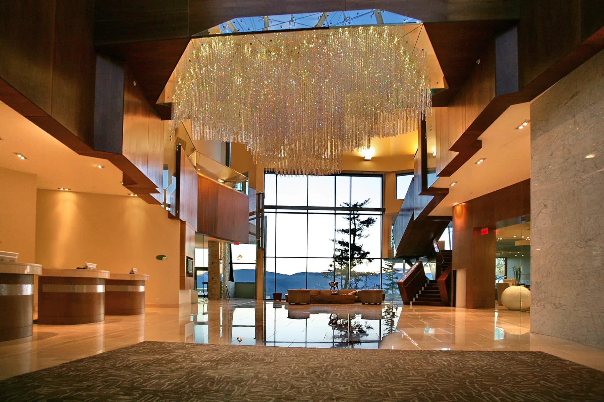 Lobby interior of Sparkling Hill Resort featuring a crystal chandelier, wooden accents, and large windows with mountain views.