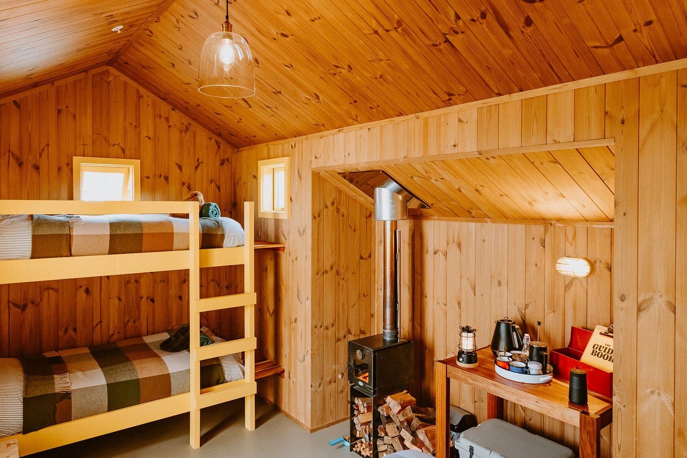 Timber-lined family cabin with bunk beds, wood-burning fire, dining area and tea station.