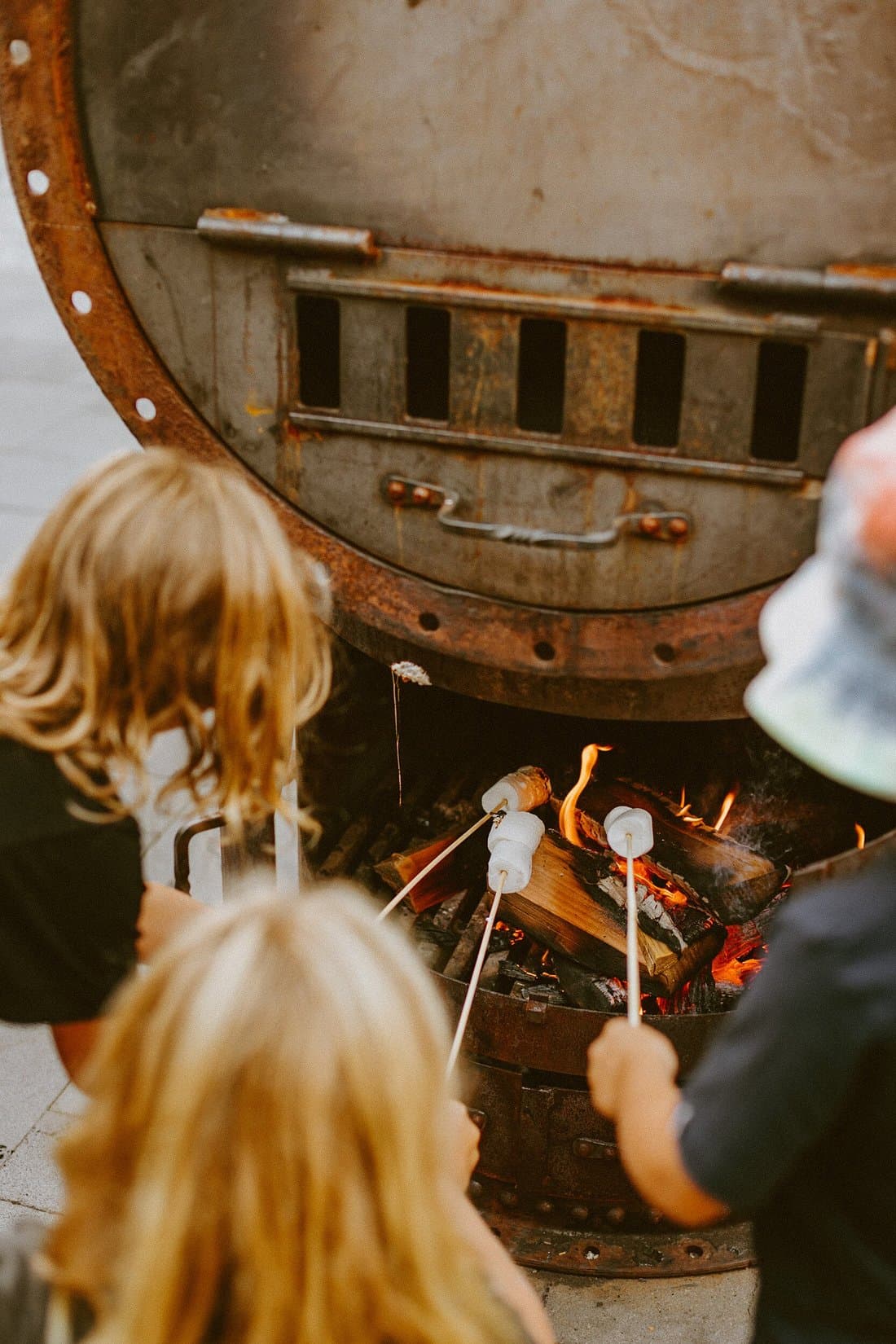 Children toasting marshmallows over an open outdoor fire at The Great Glenorchy Alpine Base Camp.