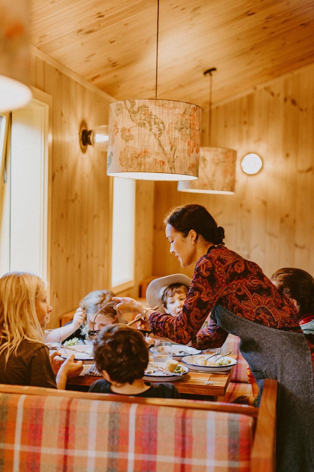 Family dining inside a warm timber-lined room at The Great Glenorchy Alpine Base Camp.
