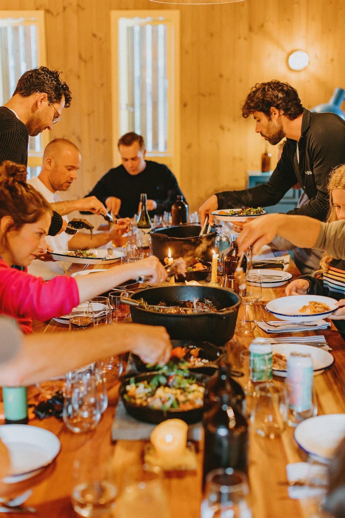 Guests sharing a candlelit meal around a long timber table inside Base Camp Kitchen.