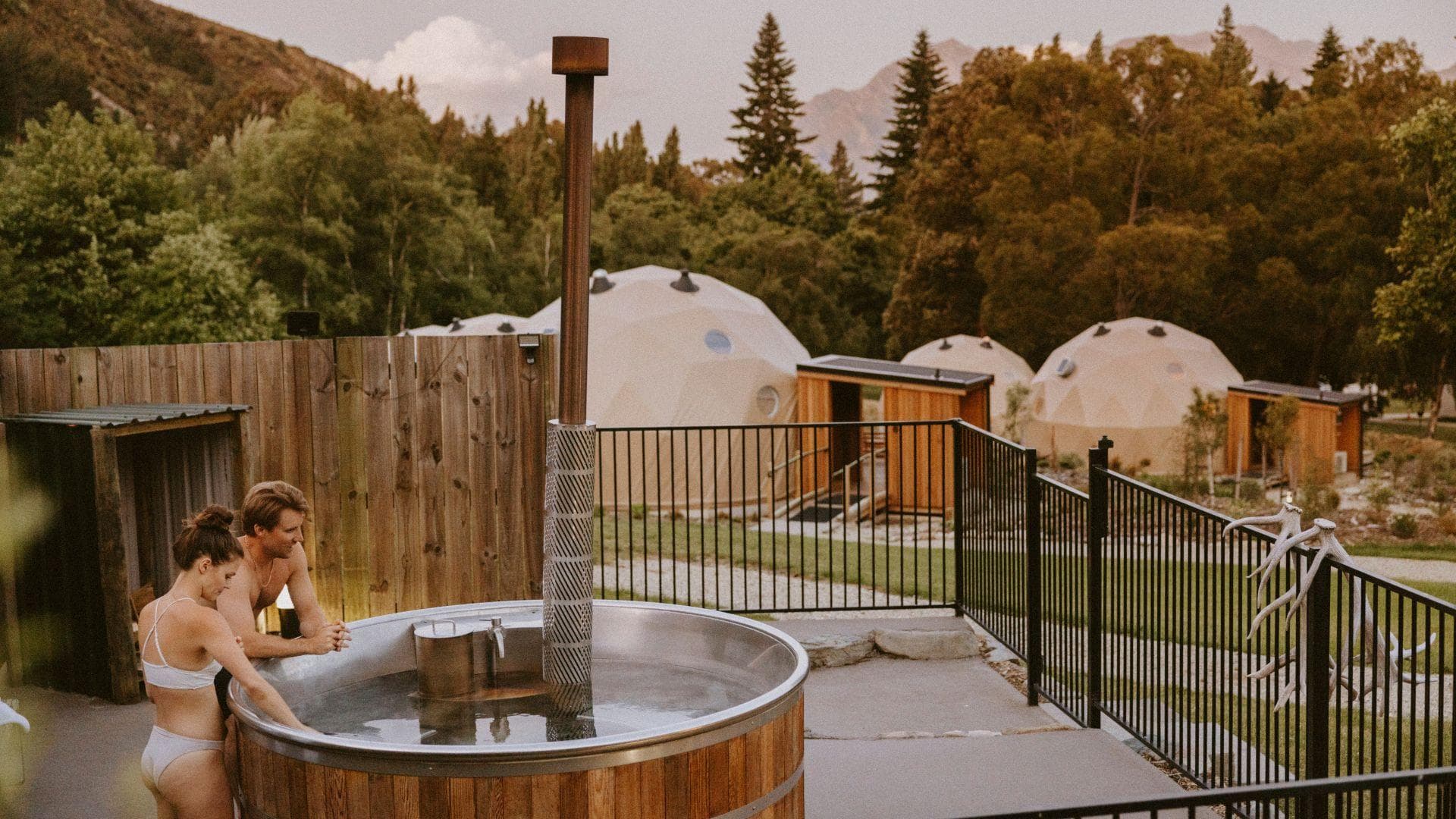 Guests relaxing in a wood-fired outdoor hot tub beside the Cross Hill Geo Domes.