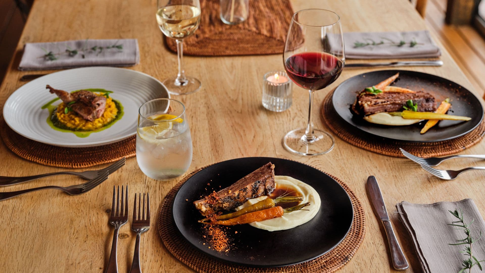 Plated dinner with wine, candles and seasonal dishes on a timber dining table at Cross Hill.