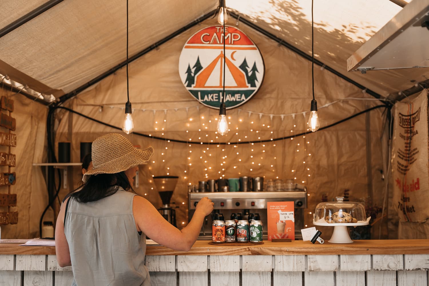 Guest ordering at The Camp food truck, with warm lights, drinks, baked goods and café signage.