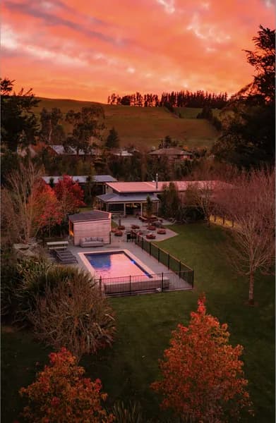 Aerial view of Manawa Retreat featuring a swimming pool, hot tub, and autumn foliage at sunset.