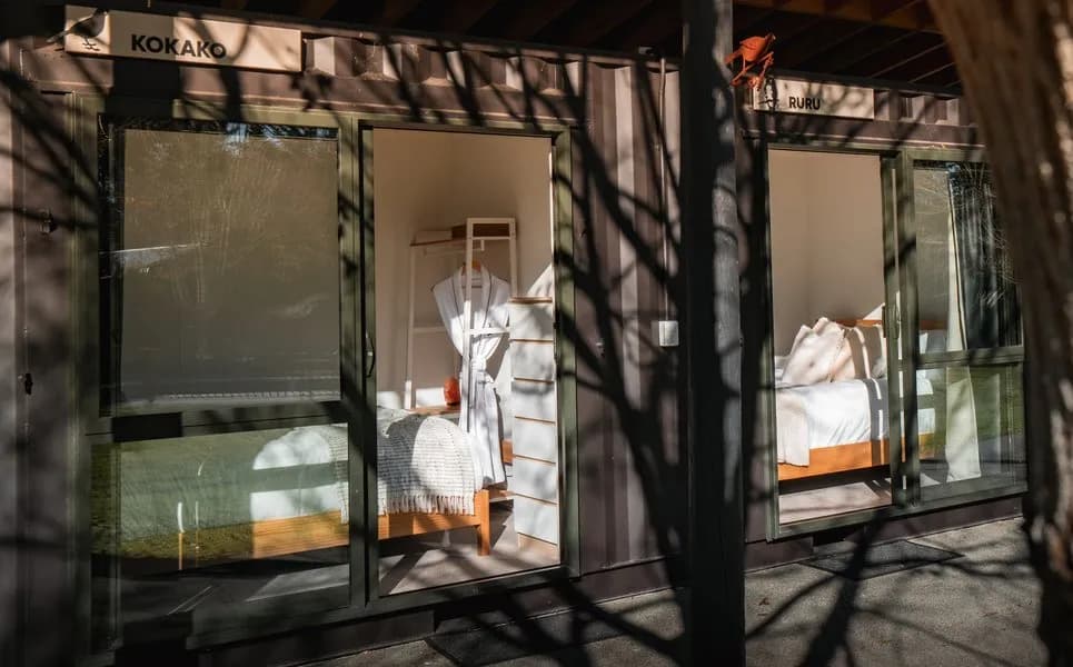 Exterior view of guest rooms, featuring timber beds, soft furnishings, and natural light.