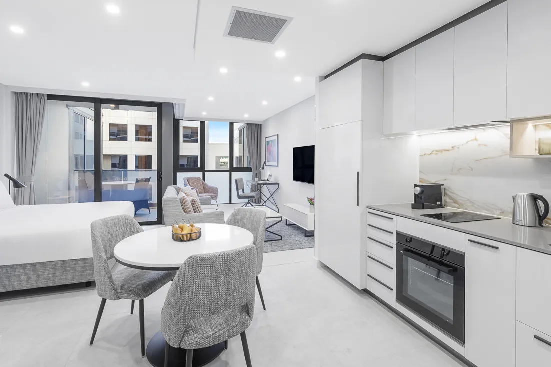 Suite interior featuring a kitchen, dining table, lounge area, and large windows.
