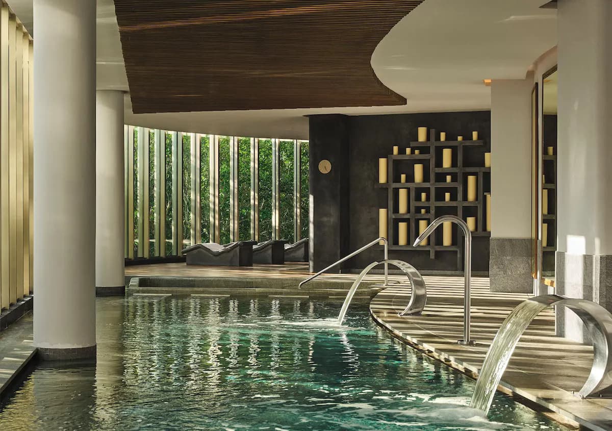 Indoor pool area with water features, wooden ceiling, and greenery visible through large windows at SHA Mexico.