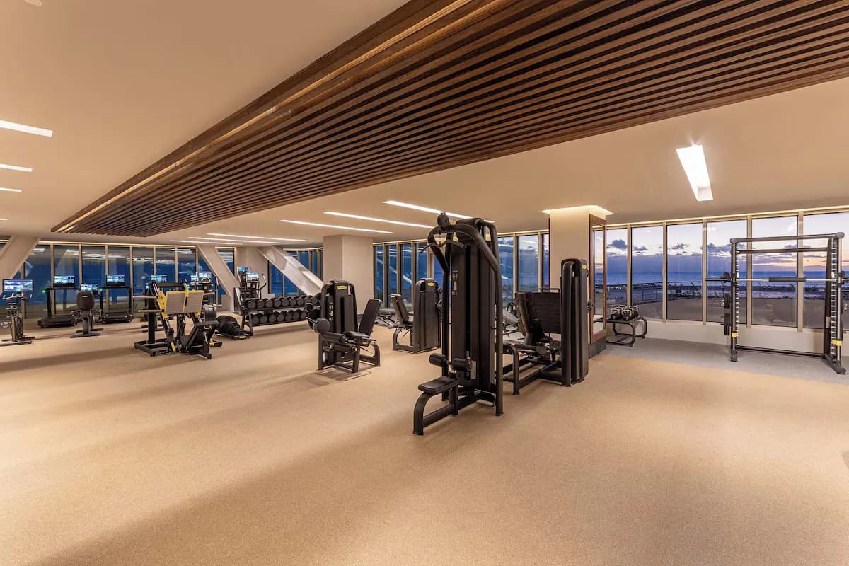 Gym interior at SHA Mexico featuring various fitness machines, free weights, and large windows with ocean views.