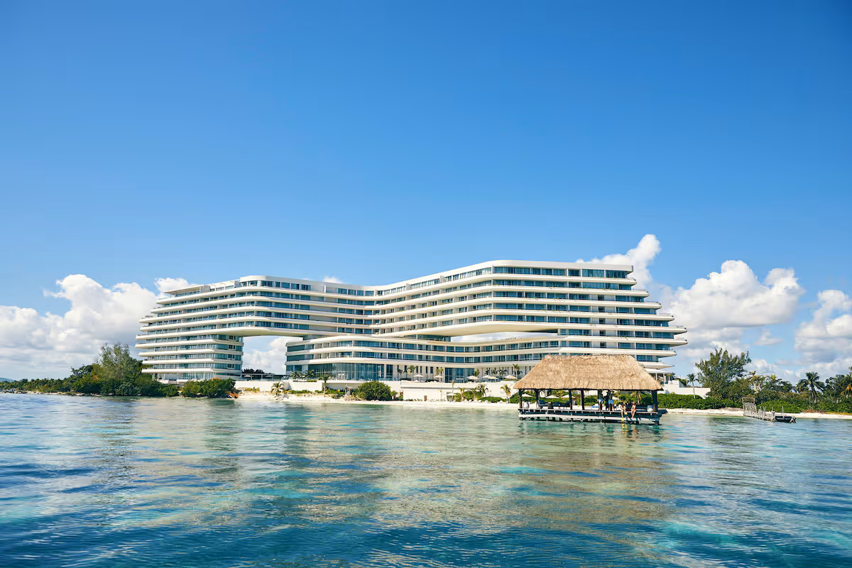 Exterior photo of SHA Mexico showing the hotel in front of clear ocean water and a white sandy beach.