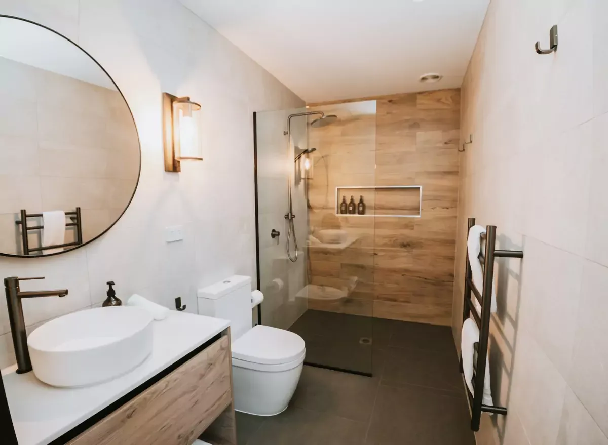 Modern Cross Hill bathroom with round mirror, timber vanity, walk-in shower and heated towel rail.