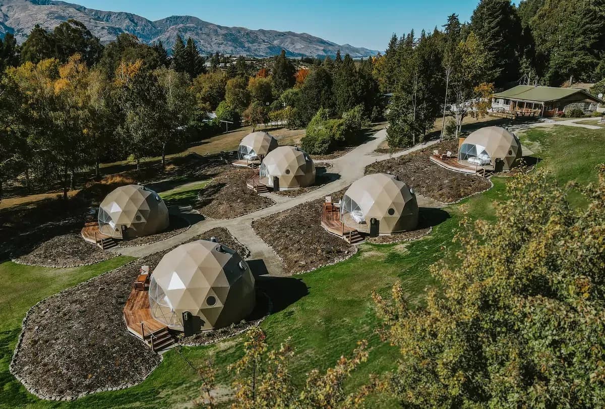 Drone view of Cross Hill Geo Domes with private decks, pathways, trees and mountain views.