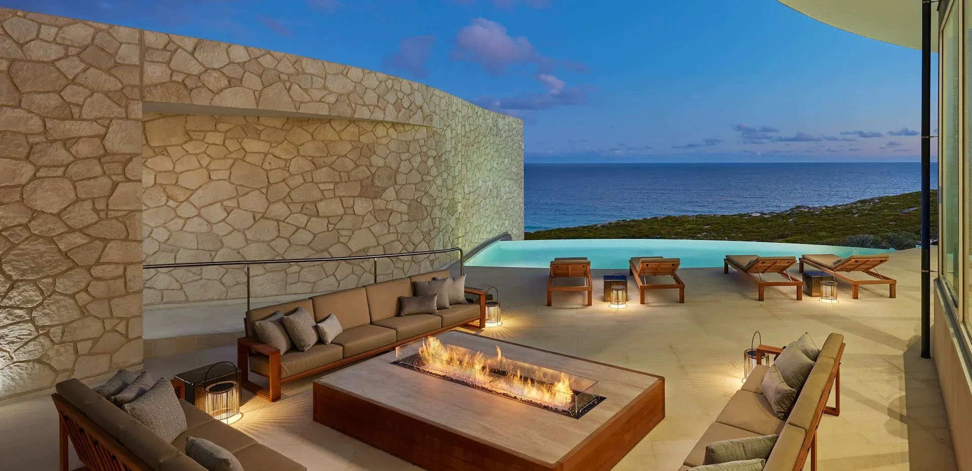 Lounge area with stone walls, sofas, fire pit, and pool area.